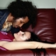 Man leaning over woman on red couch