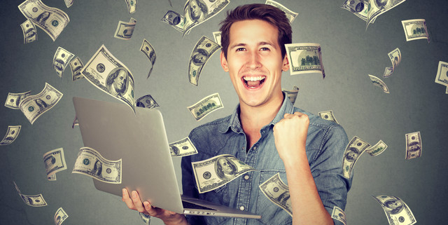 Man celebrating with laptop as money rains