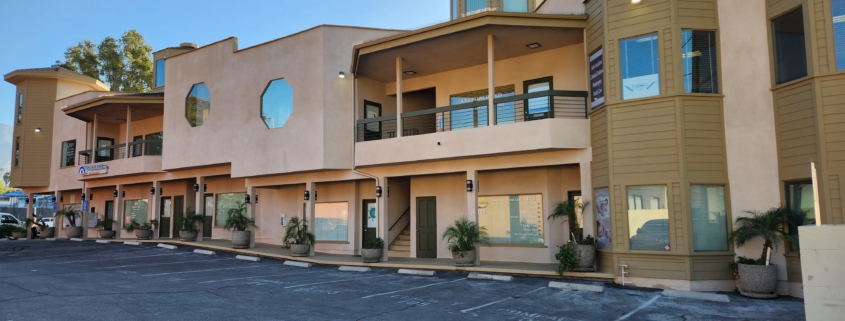 Two-story beige building with balconies and parking