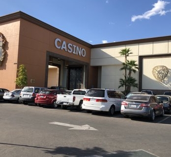 Casino entrance with parked cars and palms