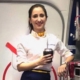 Smiling flight attendant holding drink aboard plane
