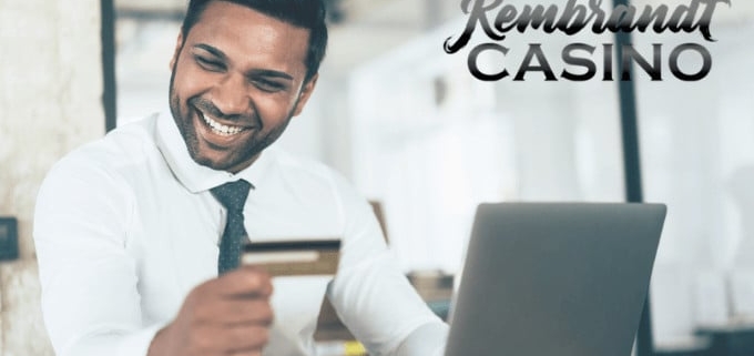 Smiling man holding credit card by laptop