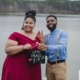 Happy couple showing engagement ring and sign