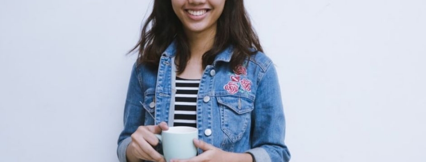 Smiling woman holding mug in denim jacket