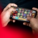 Hands holding smartphone showing slot machine game