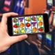 Hand holding smartphone showing slot machine game