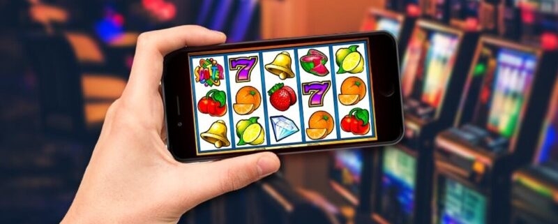 Hand holding smartphone showing online slot game