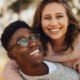 Smiling interracial couple outdoors, woman hugging man