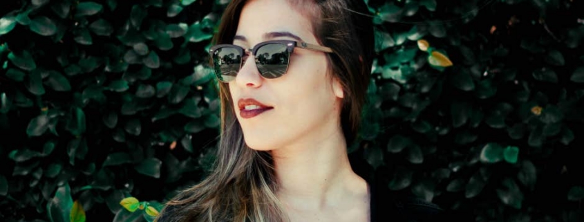 Woman wearing sunglasses against leafy background