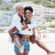 Two women laughing, piggyback on sunny beach