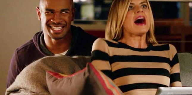 Man smiling behind surprised woman on couch