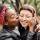 Woman kissing friend on cheek in park