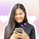 Smiling woman using smartphone with floating hearts