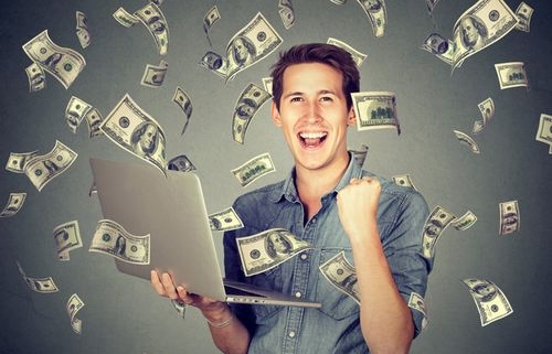 Happy man with laptop amid flying cash
