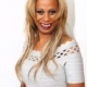 Smiling person with long blonde hair, white dress