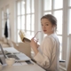 Woman holding glasses at desk, looking back