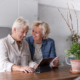 Two senior women using tablet in kitchen