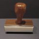 Wooden-handled rubber stamp on gray background