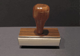 Wooden-handled rubber stamp on gray background